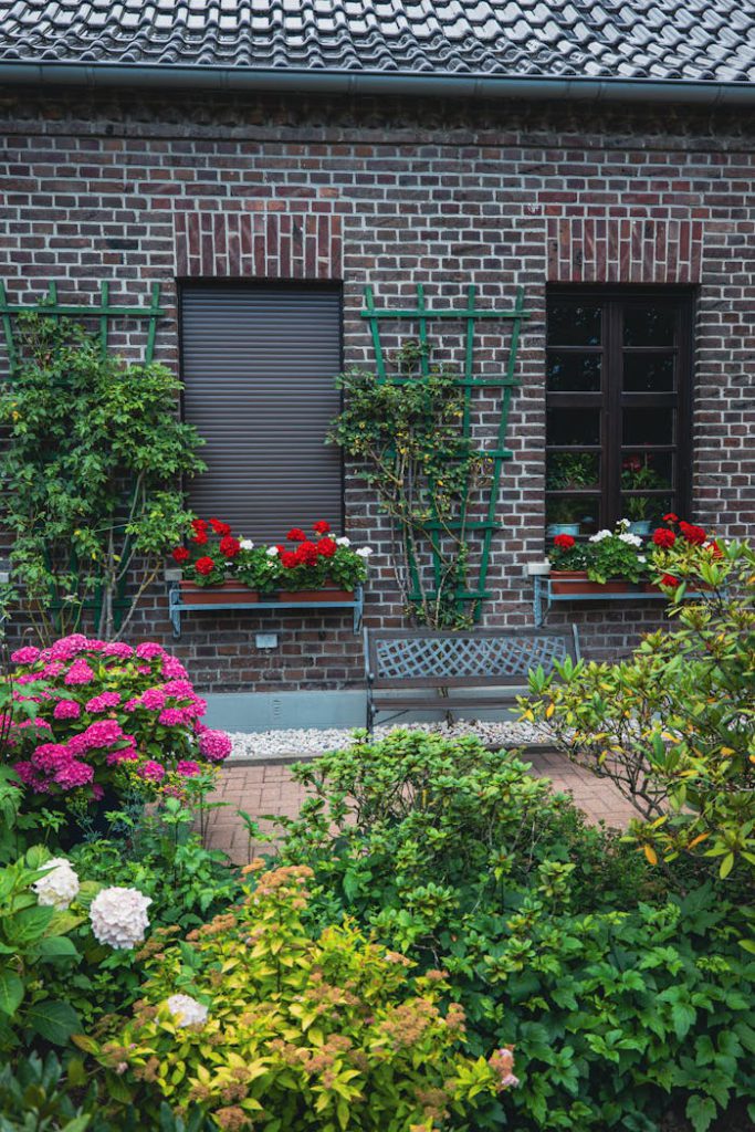A delightful garden with colorful flowers against a rustic brick house providing a serene and inviting atmosphere.